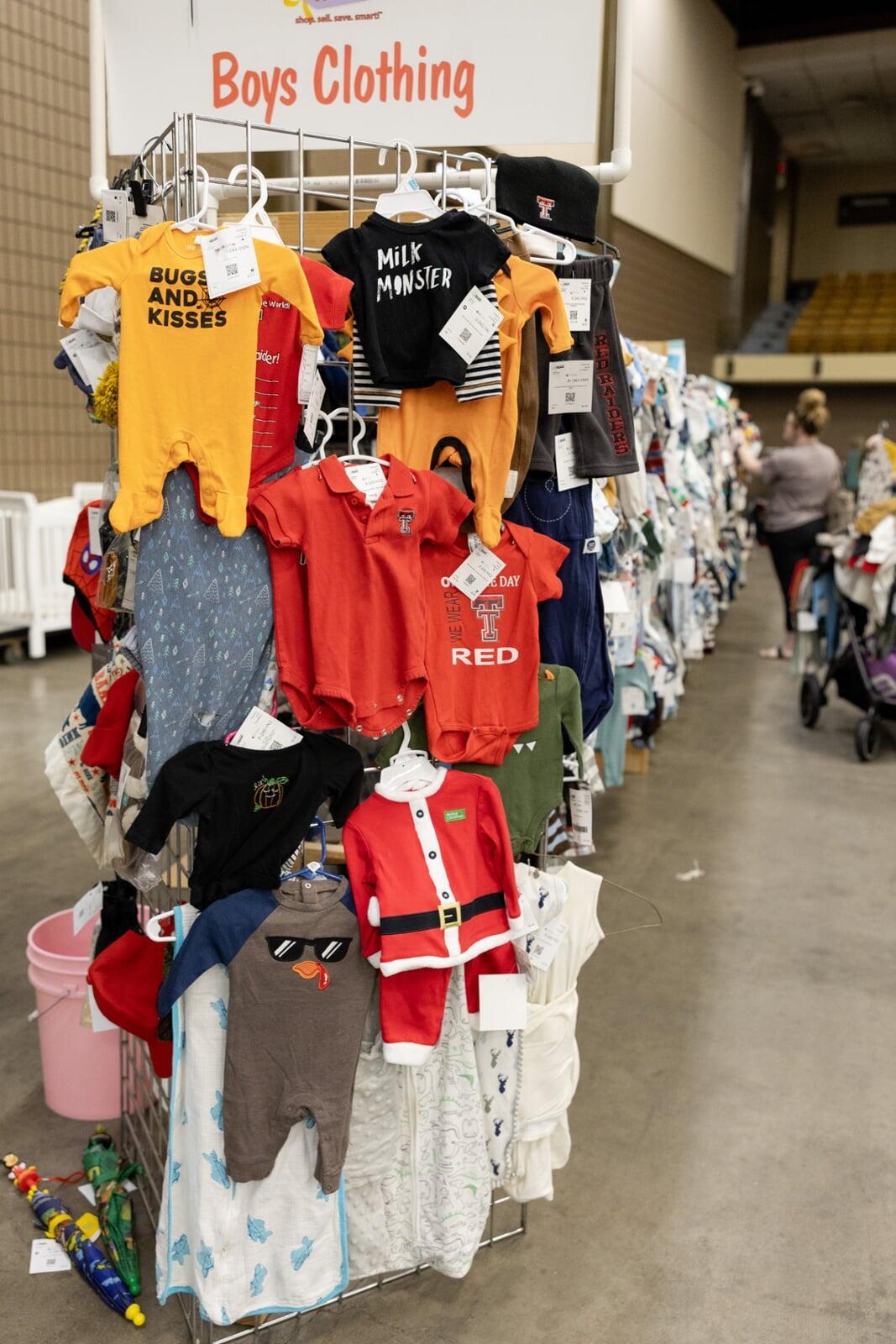 A mom and her child hug in between two rows of little girl clothes
