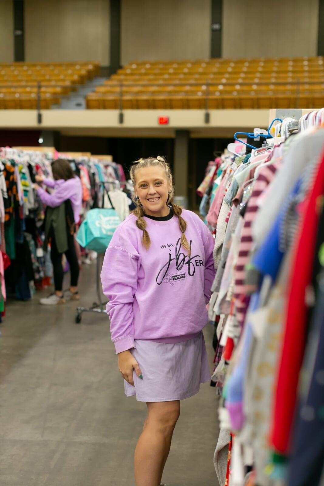 A mom and her child hug in between two rows of little girl clothes