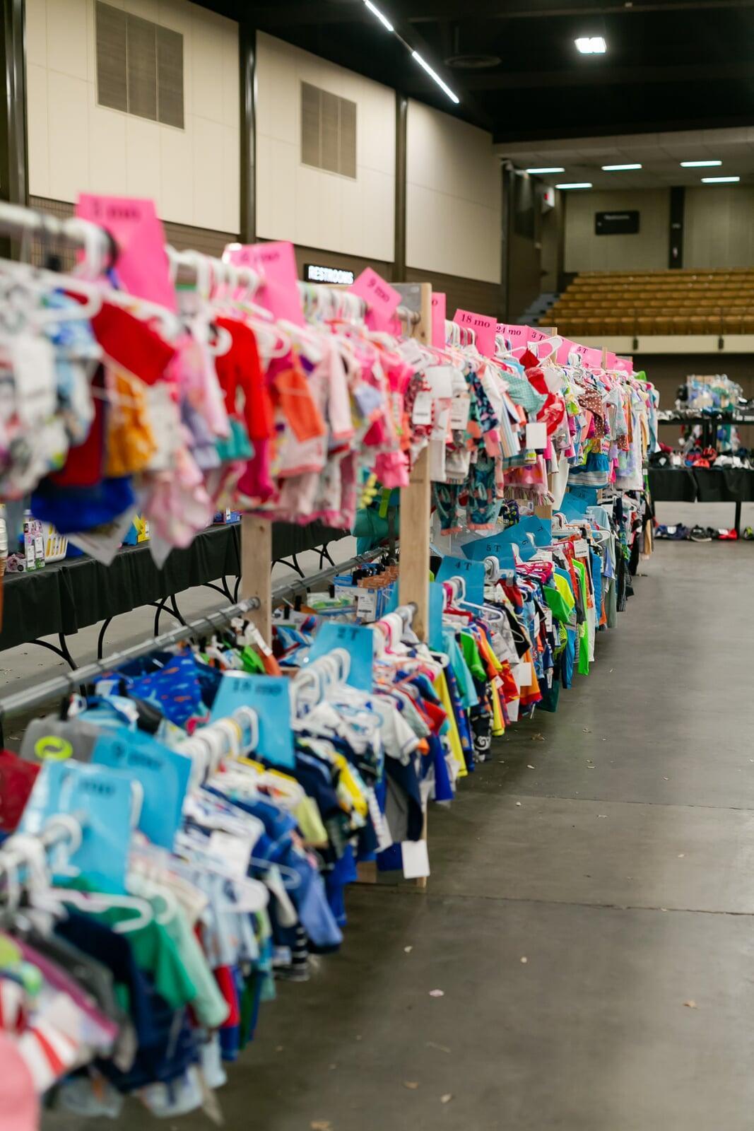 A mom and her child hug in between two rows of little girl clothes