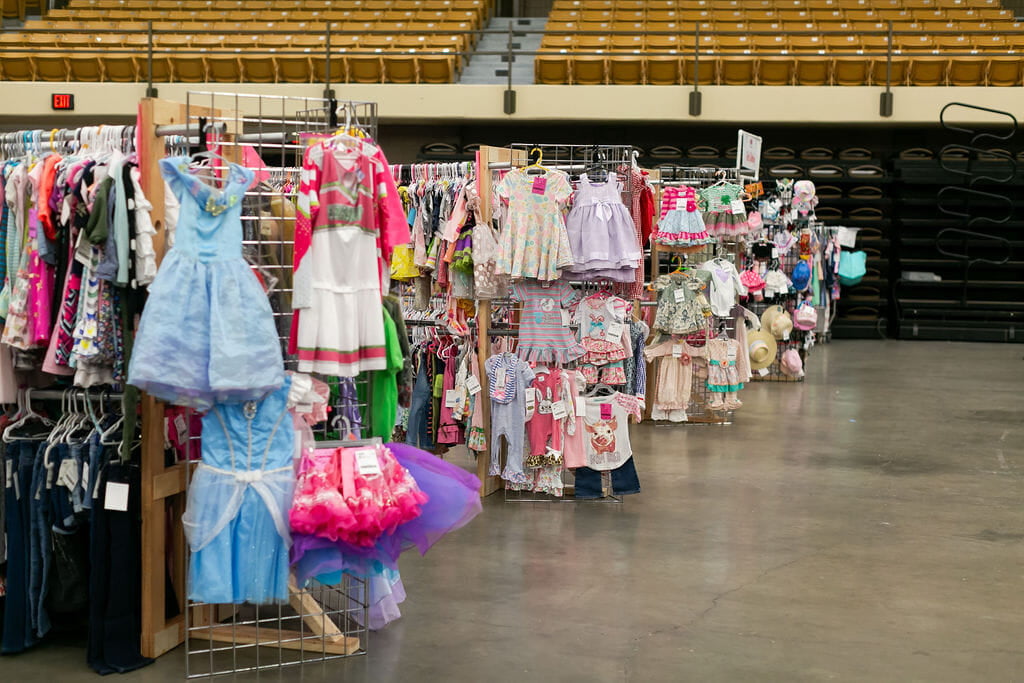 Tricycles, scooters and toys lined up on a table waiting for shoppers to attend the sale.